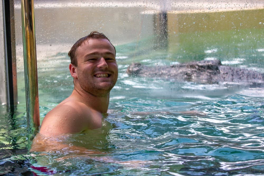 Harry Wilson swimming with a croc as part of the 'Reds to Region' Tour. Photo: QRU/Tom Mitchell