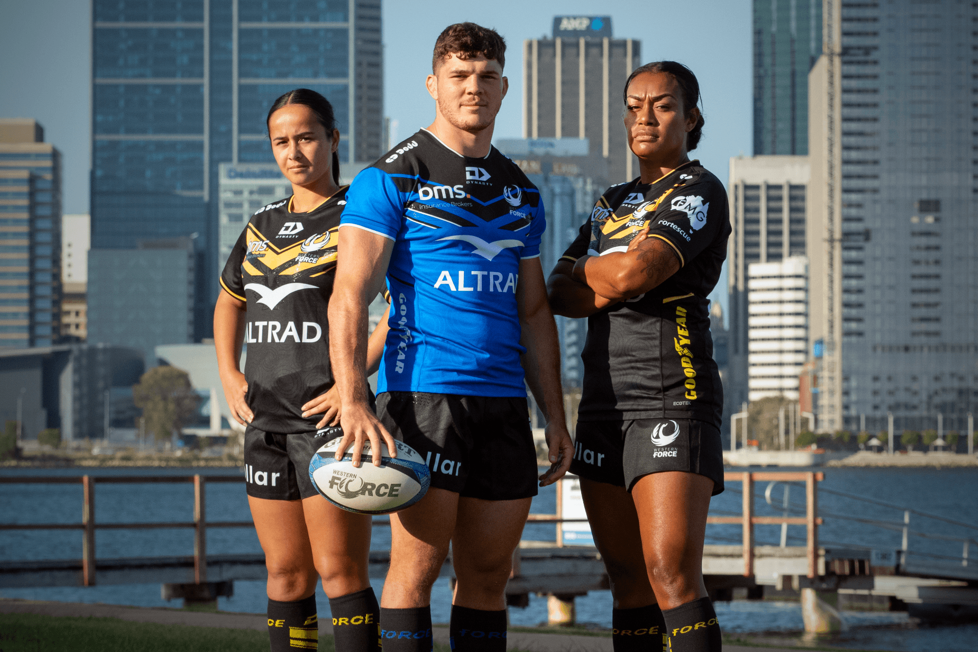 Nicole Ledington, Carlo Tizzano and Sara Ravatudei pose in the Western Force 2024 playing jerseys in front of the Swan River and Perth city skyline.