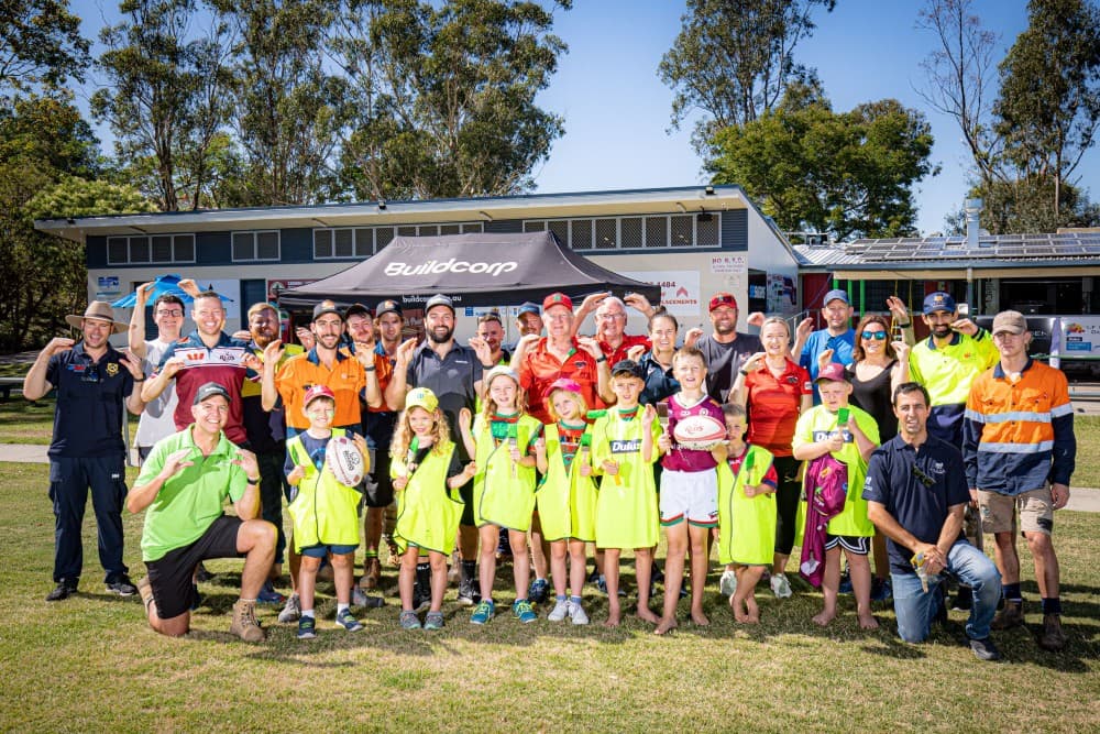 Tradies, Buildcorp Queensland General Manager Mike Currie (bottom left), club volunteers, Shannon Parry and Redlands juniors share a Mud Crabs' salute at the working bee. Photo: Brendan Hertel, QRU