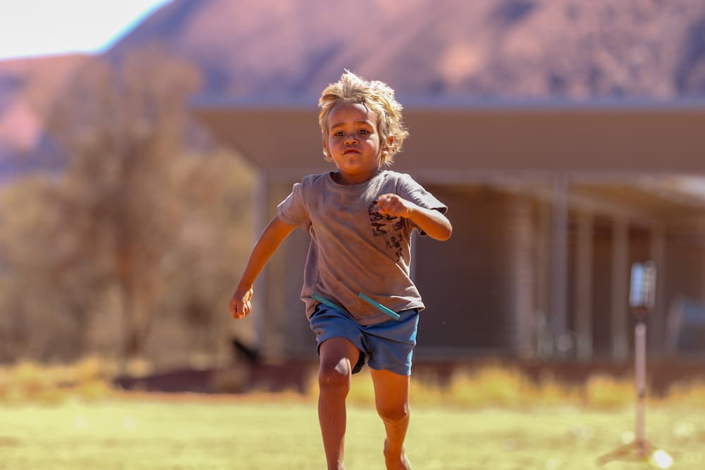 A youngster sprints in front of Uluru on the DreamBigTime tour. Photo: Marty Cambridge/RUGBY.com.au