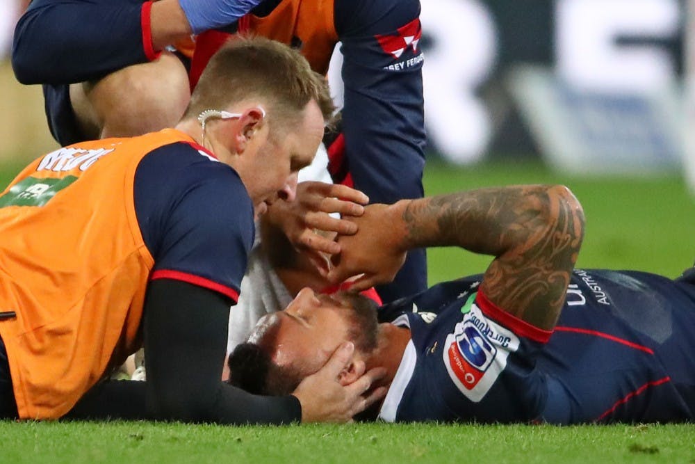 A trainer attends to Quade Cooper after he was concussed making a tackle on Reds captain Samu Kerevi. Photo: Getty Images 